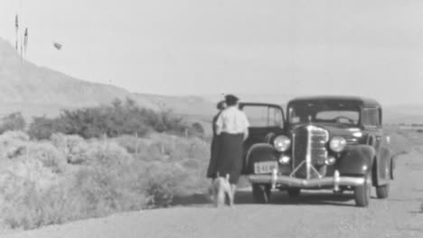 Two-Women-Travel-with-Dog-in-Classic-Car-on-a-Road-Surrounded-by-Mountains
