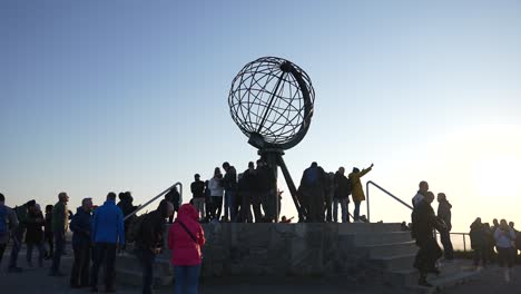 Menschenmenge-Unter-Dem-Globus-Denkmal-Am-Nordkap-Von-Norwegen-Bei-Sonnenuntergang,-Zeitlupe