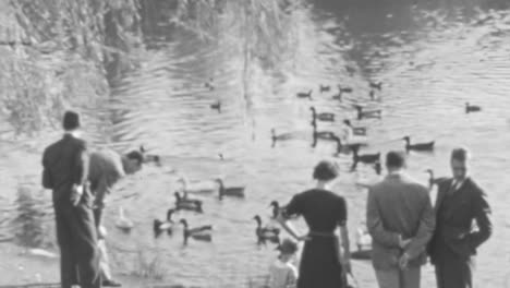 Group-of-People-Enjoy-Free-Time-at-the-Waters-Edge-Watching-Birds-in-1930s-BW