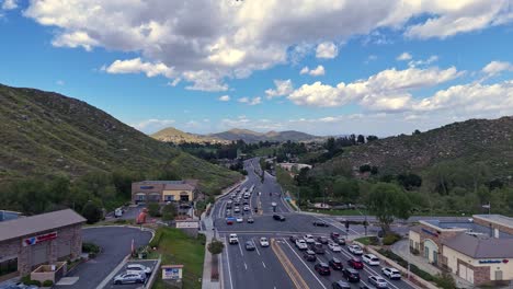 Drone-Flight-Over-Traffic-at-Railroad-Canyon-Road-and-Canyon-Hills-Road-in-Lake-Elsinore-California-Traffic-stopped-at-light-before-starting-to-flow-clouds-overhead