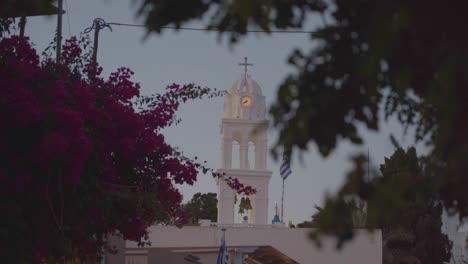 Malerischer-Blick-Auf-Die-Griechische-Flagge,-Die-In-Mykonos,-Griechenland,-Mit-Einer-Griechisch-orthodoxen-Kirche-Und-Einer-Blauen-Kuppel-Im-Hintergrund-Weht