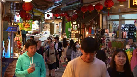 People-strolling-through-the-narrow-old-street-lined-with-food-stalls,-souvenir-shops-and-gift-stores,-exploring-the-charming-Jiufen-mountain-village-town,-popular-tourist-attraction-of-Taiwan