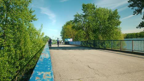People-strolling-and-cycling-on-a-vibrant-blue-bridge-at-Jarun-Lake,-Zagreb-Croatia