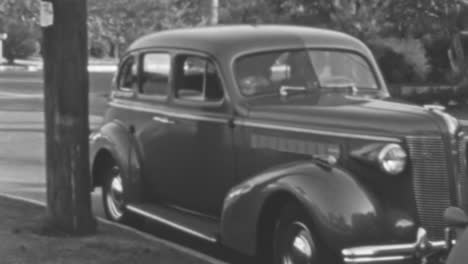 Woman-Opens-the-Front-Passenger-Door-of-a-Classic-Car-Parked-on-the-Street-in-BW