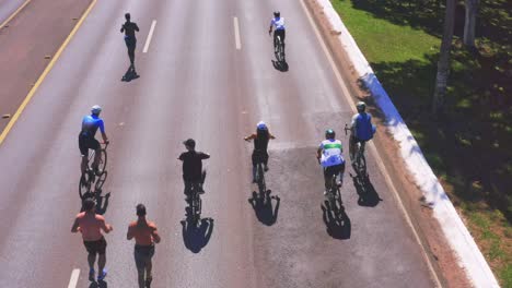 Vista-Aérea-De-Gente-Corriendo-Y-Andando-En-Bicicleta-Por-Un-Carril-Iluminado-Por-El-Sol.