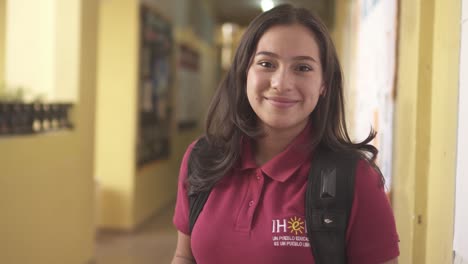 Retrato-De-Una-Estudiante-Adolescente-Hispana-Sonriendo-A-La-Cámara-En-Una-Universidad-De-área-Urbana