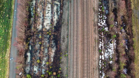 Vías-Férreas-Dobles-En-Invierno,-Bordeadas-De-Zonas-Nevadas-Y-Vegetación,-Vista-Aérea