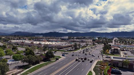 Drone-Diagonal-Approach-to-the-Intersection-of-Winchester-Road-and-Margarita-Road-in-Temecula-California-With-oncoming-traffic-starting-at-a-stopped-position-before-proceeding-dramatic-clouds