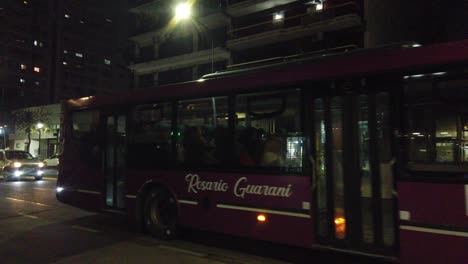 Nighttime-Buses-drive-in-busy-Rivadavia-Street-of-Buenos-Aires-City,-Traffic-in-South-American-Capital-of-Argentina,-cars,-buildings,-night-lighting