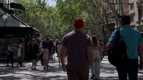 Bulliciosa-Escena-De-Una-Calle-En-La-Rambla,-Barcelona,-Con-Peatones-Y-árboles-Sombreados,-Día-Soleado