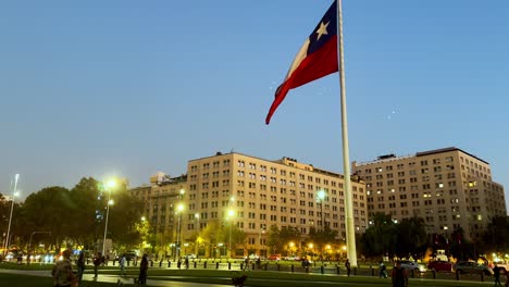 Chilean-flag-waving-at-dusk,-La-Moneda-Palace-in-Santiago,-clear-evening-sky