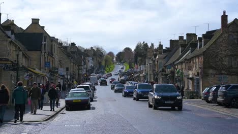 Traffic-and-tourists-on-High-Street,-The-main-road-in-Burford,-Cotswold-Hills-in-Oxfordshire-UK---March-2024