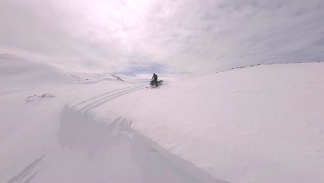 Vista-Aérea-FPV-De-Motos-De-Nieve-A-Través-De-Una-Pendiente-Cubierta-De-Nieve-Cerca-Del-Pico-Sharkstooth,-Colorado