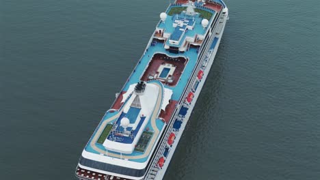 top-down-perspective-of-a-large-cruise-ship-in-the-center-of-the-frame,-dwarfing-the-surrounding-turquoise-ocean