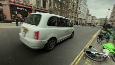 White-London-Taxi-rounds-corner-onto-The-Haymarket,-London,-Day