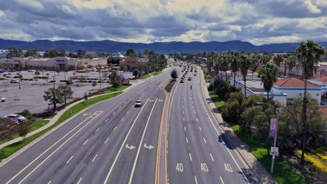 Vuelo-De-Drones-Hacia-Adelante-Temecula-California-Sobre-Winchester-Road-Cerca-De-Margarita-Road-Sobre-El-Divisor-Central-Mientras-El-Tráfico-Fluye-En-Ambas-Direcciones-Con-Un-Peatón-Imprudente-Cruzando-La-Calle-Entre-Los-Autos