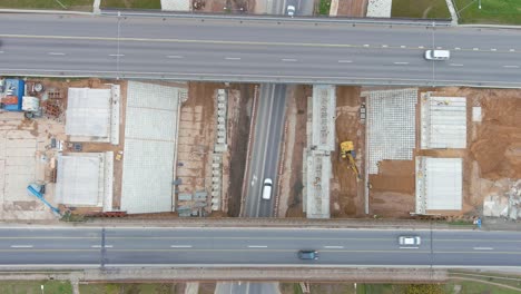 Highway-bridge-under-construction-and-road-bellow,-aerial-top-down-view