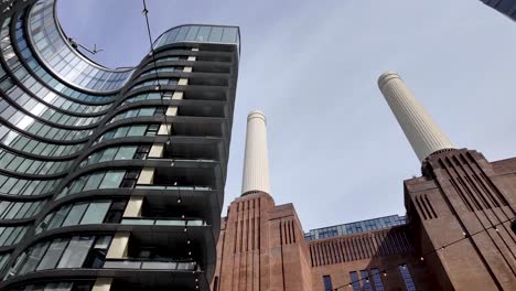 Looking-Up-At-Wavy-Building-Along-With-Chimney-Towers-Of-Battersea-Power-Station