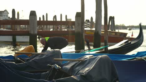 Person-Entdeckt-Schwimmende-Gondel,-Die-An-Holzmast-In-Venedig-Festgeschnallt-Ist,-Am-Frühen-Morgen