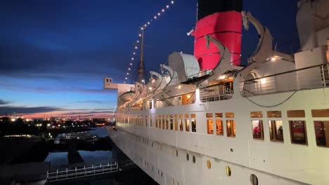 Exterior-Lateral-Del-Rms-Queen-Mary-Al-Atardecer-En-Long-Beach,-California,-Toma-Panorámica