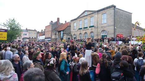 Busy-streets-packed-with-crowds-of-people-watching-Beltane-May-Day-celebrations-in-Glastonbury-town,-Somerset-UK
