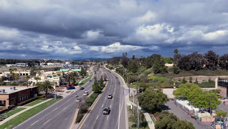 Drone-Crossing-Winchester-Road-at-Margarita-Road-in-Temecula-California-Looking-East-Sunny-Day-with-Moody-Clouds-as-Traffic-flows-Shopping-centers-on-each-side