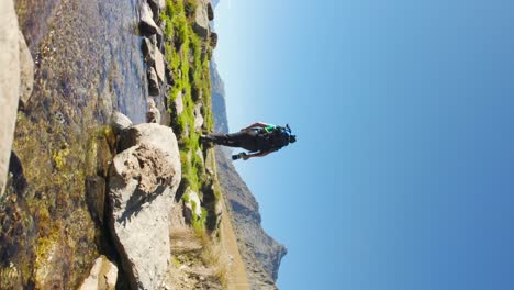 Caminata-Masculina-Sobre-Pequeñas-Rocas-Pasando-Por-Un-Arroyo-En-La-Región-De-Valmalenco,-Italia