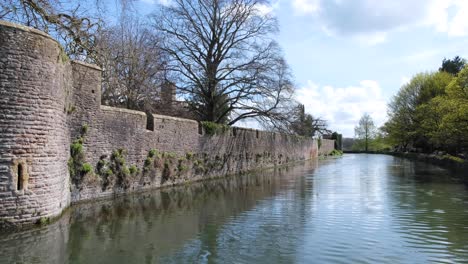 Exterior-view-of-outer-wall-of-Bishop's-Palace-surrounded-by-water-moat-in-city-of-Wells,-Somerset,-England