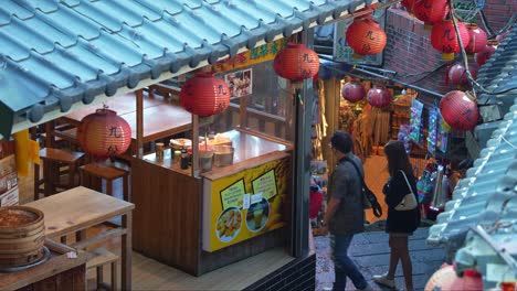 Personas-Navegando-Por-El-Laberinto-De-Calles-Estrechas-Y-Escaleras-Empinadas,-Explorando-El-Encantador-Pueblo-De-Montaña-De-Jiufen-Con-Tiendas-Y-Puestos-De-Comida-A-Lo-Largo-Del-Camino