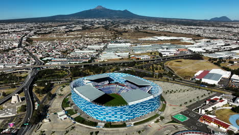 Aerial-view-circling-the-Football-Soccer-Stadium,-in-sunny-Puebla,-Mexico