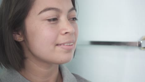 Close-up-of-teenage-latin-woman-smiling-in-front-of-camera-while-combing-her-hair