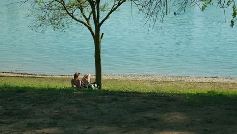 Peaceful-relaxation-by-Jarun-Lake,-Zagreb,-as-a-young-woman-enjoys-a-sunny-lakeside-retreat