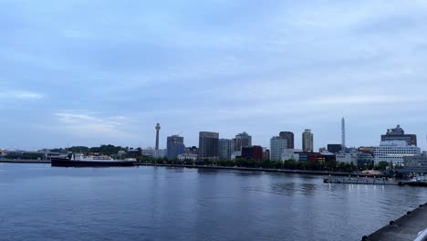 Dawn-breaking-over-calm-river-with-city-skyline-and-clouds