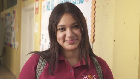 Portrait-of-young-latin-female-student-smiling-at-camera-in-urban-area-school