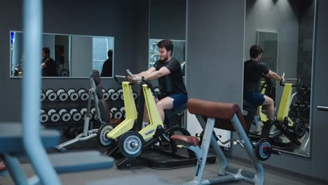 Múltiples-Reflejos-De-Espejo-En-El-Gimnasio-Mientras-Los-Hombres-Hacen-Ejercicio-De-Espalda-Con-Una-Máquina-De-Remo