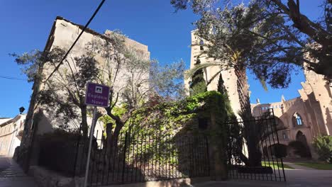 La-Iglesia-Nunca-Terminada-De-Son-Servera,-Entrada-Desde-La-Calle-Hasta-La-Primera-Mirada-A-La-Piedra-Caliza-Sobre-Fondo-De-Cielo-Azul