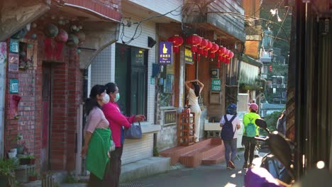 Tourists-stroll-through-the-charming-narrow-streets,-exploring-the-sights-and-soaking-in-the-atmosphere-of-Jiufen's-historic-mountain-town,-static-shot-of-the-popular-tourist-attraction-in-Taiwan