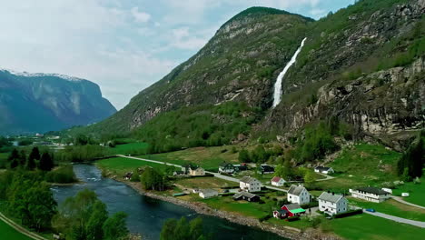 Aerial-view-of-a-river,-houses-and-a-waterfall,-sunny-day-in-Flam,-Norway