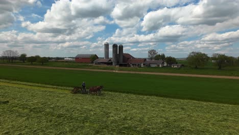 Drone-shot-of-traditional-Amish-Farmer-with-horses-plowing-field-in-American-Countryside