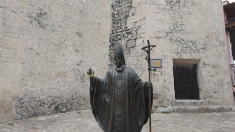 Tilt-up-of-Catholic-priest-or-pope-holding-staff-with-crucifixion-in-courtyard,-Cartagena
