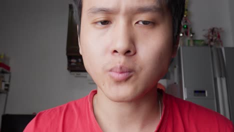 Man-in-red-shirt-enjoying-a-quick-snack-indoors,-close-up