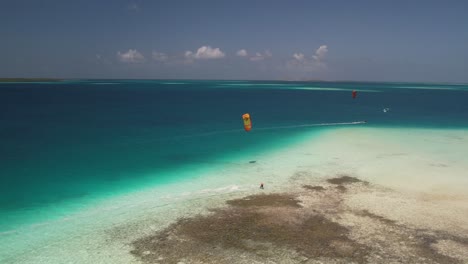 Un-Kitesurfista-Amarillo-Deslizándose-Sobre-Las-Aguas-Cristalinas-De-Los-Roques,-Venezuela,-Vista-Aérea