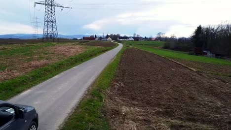 Family-car-traveling-past-farmland-toward-small-town