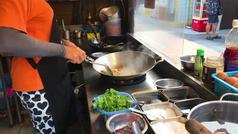 Comida-Callejera-Tailandesa,-La-Cocinera-Está-Cocinando-Albahaca-Con-Carne-De-Cangrejo-Salteada-En-El-Mercado-De-Pescado-De-Bangsaen,-Uno-De-Los-Lugares-Famosos-De-La-Provincia-De-Chon-Buri-En-Tailandia