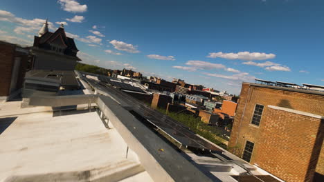 Slow-drone-flight-over-apartment-block-in-city-with-solar-panels-on-roof-at-sunset