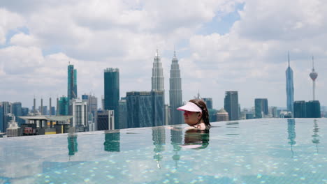 Woman-Enjoying-Views-Of-Iconic-Towers-From-Infinity-Pool-In-Kuala-Lumpur,-Malaysia