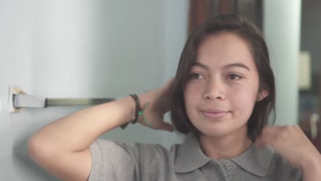 Teenager-lateinamerikanische-Frau-Lächelt-Vor-Dem-Spiegel,-Während-Sie-Ihr-Haar-Streichelt