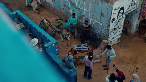 Camel-ride-vendors-having-a-chat-with-tourists-in-the-corner-of-market-street-in-Nubian-village,-Aswan,-Egypt