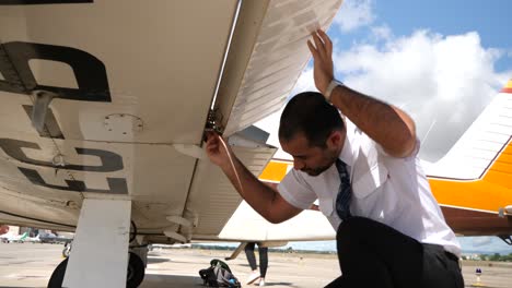 Eine-Nahaufnahme-Eines-Piloten-Unter-Dem-Flügel-Seines-Flugzeugs,-Der-Die-Klappe-überprüft