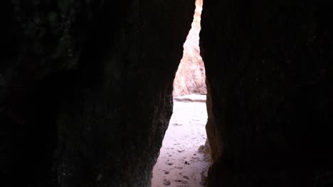 Tourist-POV-Walking-Through-A-Narrow-Rock-Tunnel-Leading-To-The-Beach-In-Lagos,-Algarve-Region-Of-Southern-Portugal